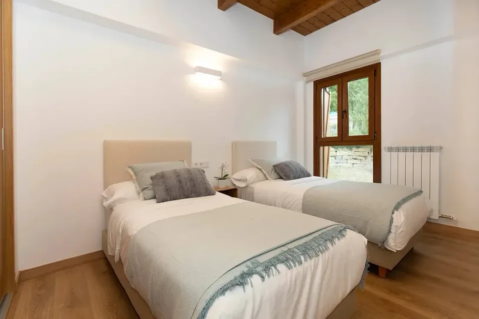 Twin bedroom. Two beds and a window that brings in the light: room to share and rest.